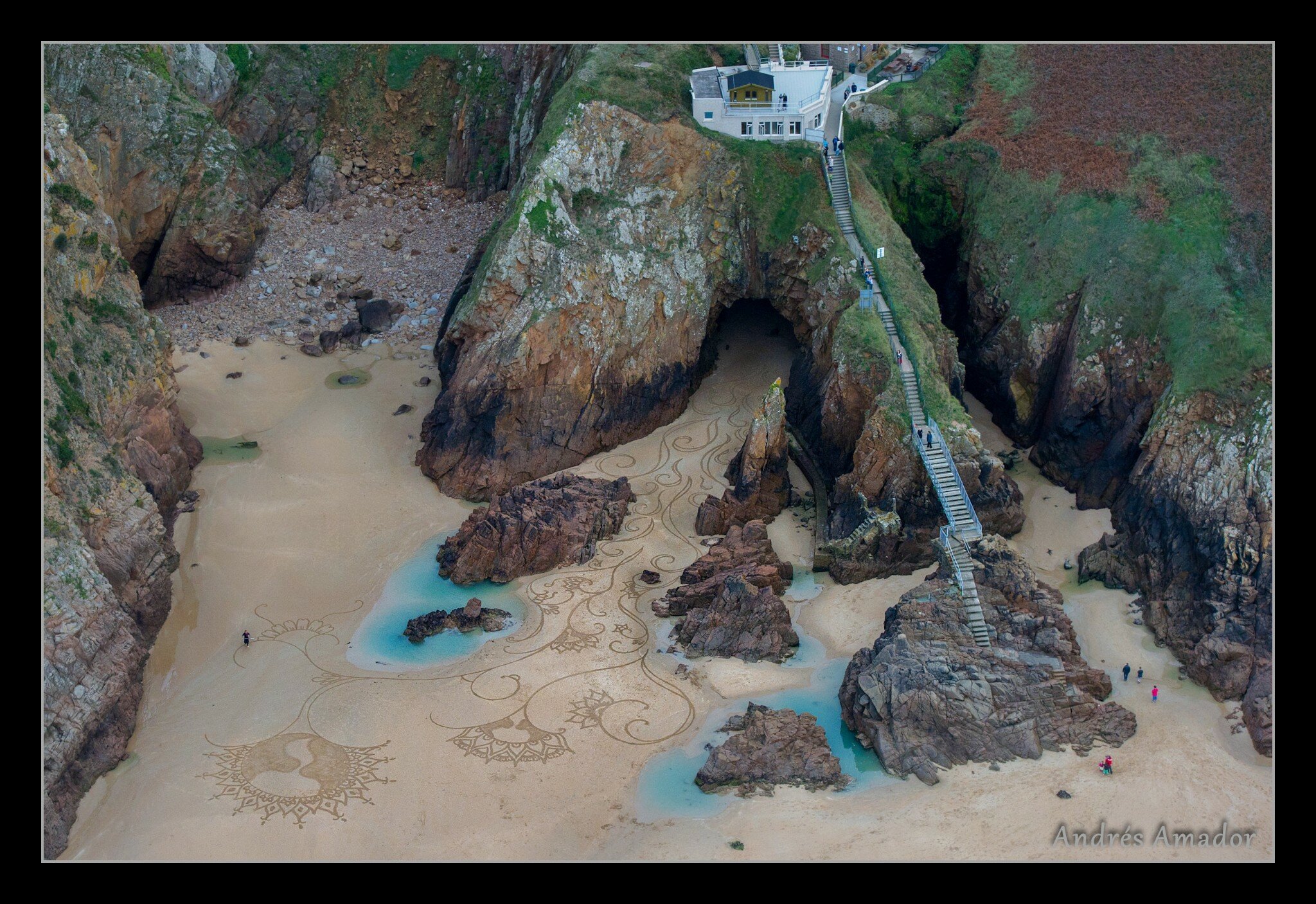 Inspired by the cave and the narrow channel leading from the cave to the larger beach. I started way at the back of the cave where the sand started. In my mind the cave was breathing flames which turned into vines, then flowers off of which bud planets and stars. Plemont Beach, Island of Jersey. during the MyMemory.com World Beach Art Championships.